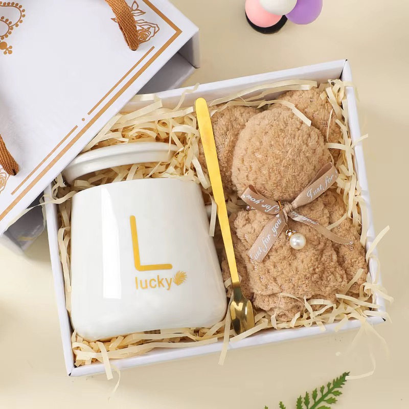 Off-white mug, soft blanket and gold spoon arranged in a gift box