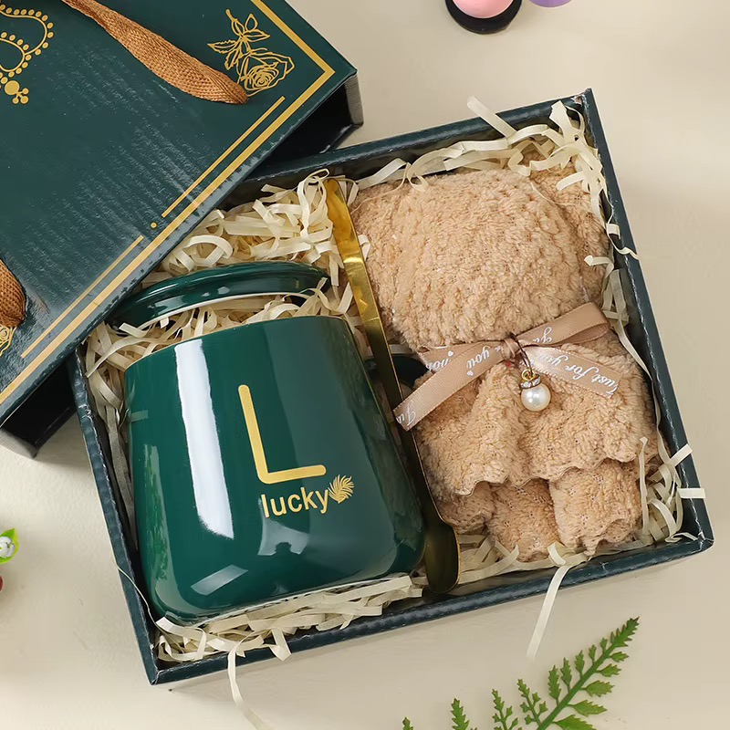 Green mug, soft blanket and gold spoon arranged in a gift box